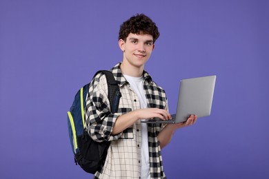 Photo of Portrait of student with backpack and laptop on purple background
