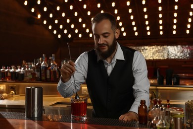 Photo of Bartender making fresh alcoholic cocktail at bar counter