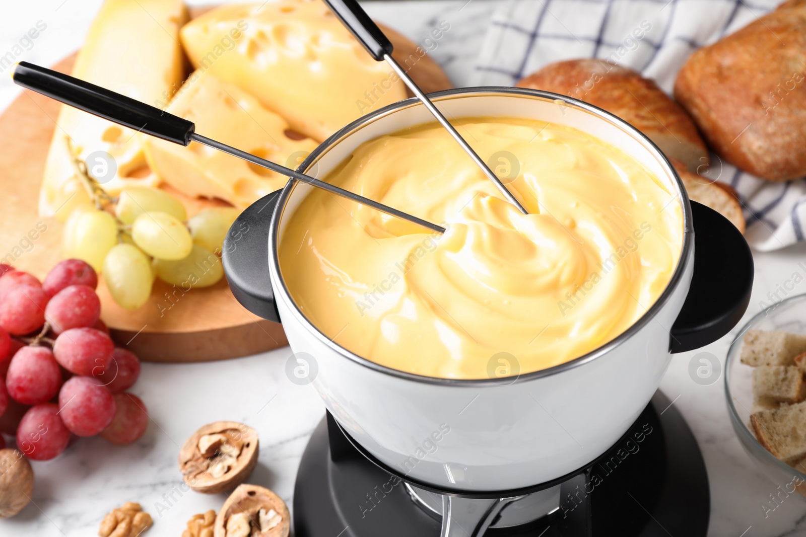 Photo of Pot of delicious cheese fondue and forks on table