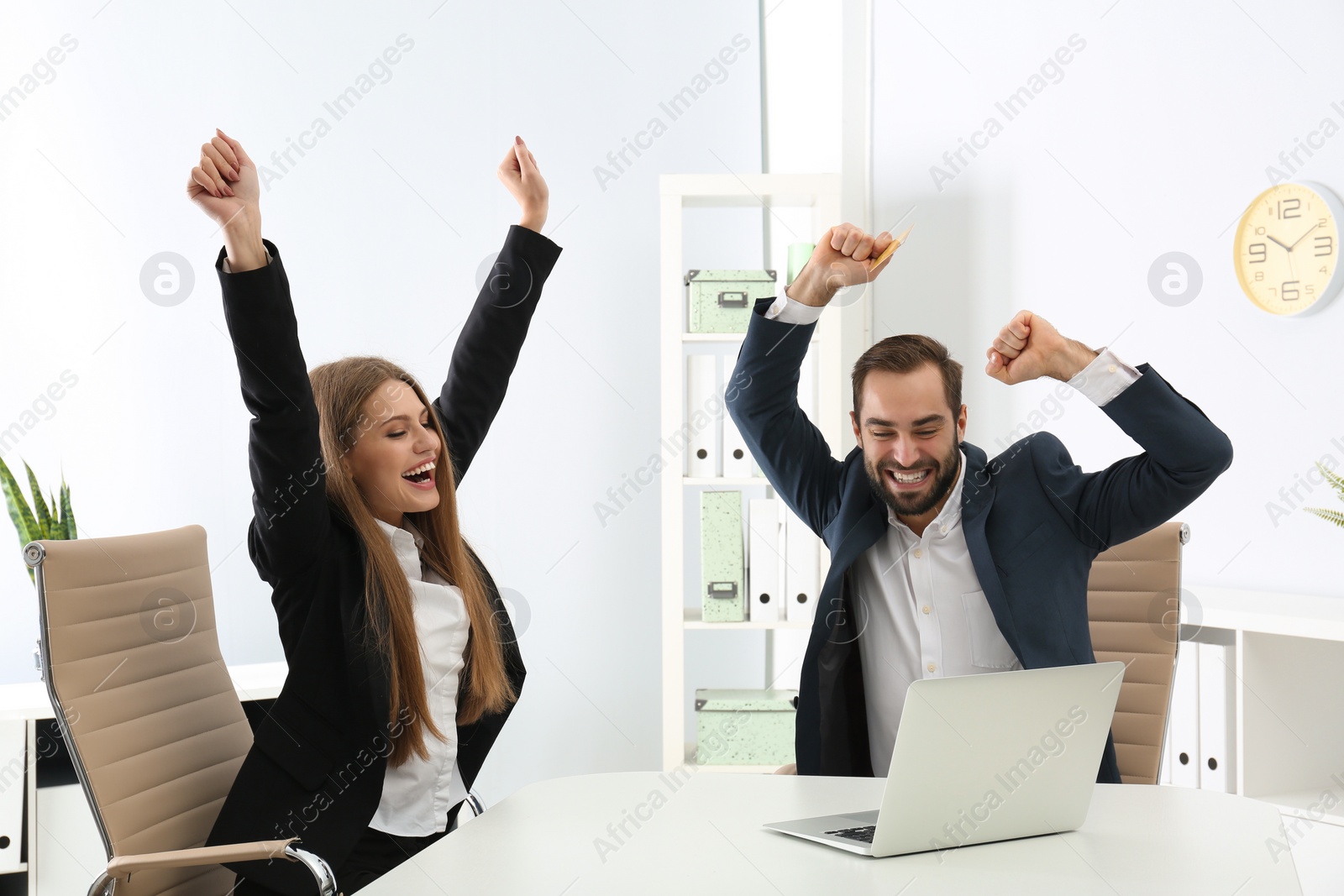 Photo of Emotional young people with credit card and laptop celebrating victory in office