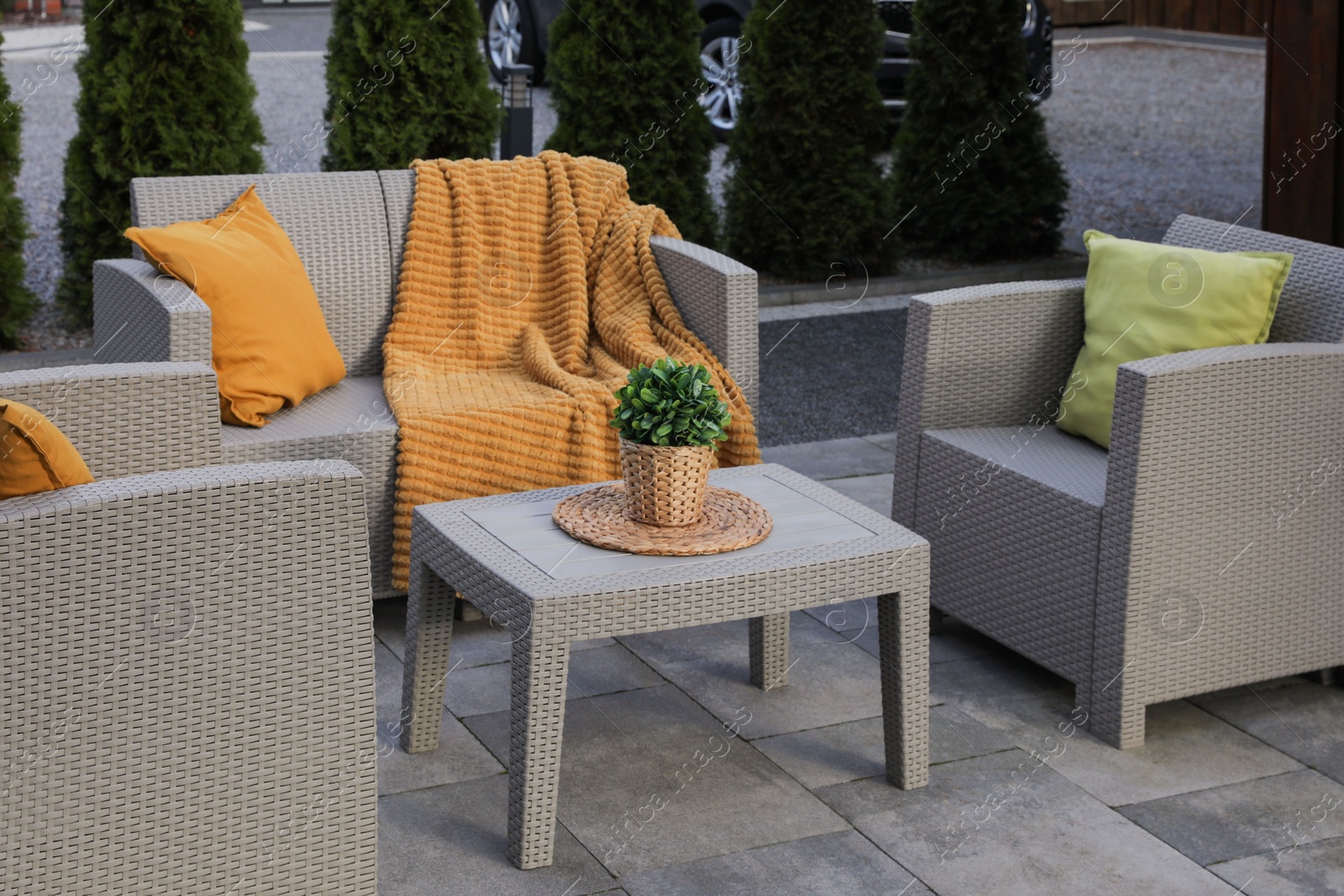 Photo of Beautiful rattan garden furniture, soft pillows and houseplant outdoors