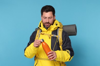 Photo of Man with backpack and thermo bottle on light blue background. Active tourism