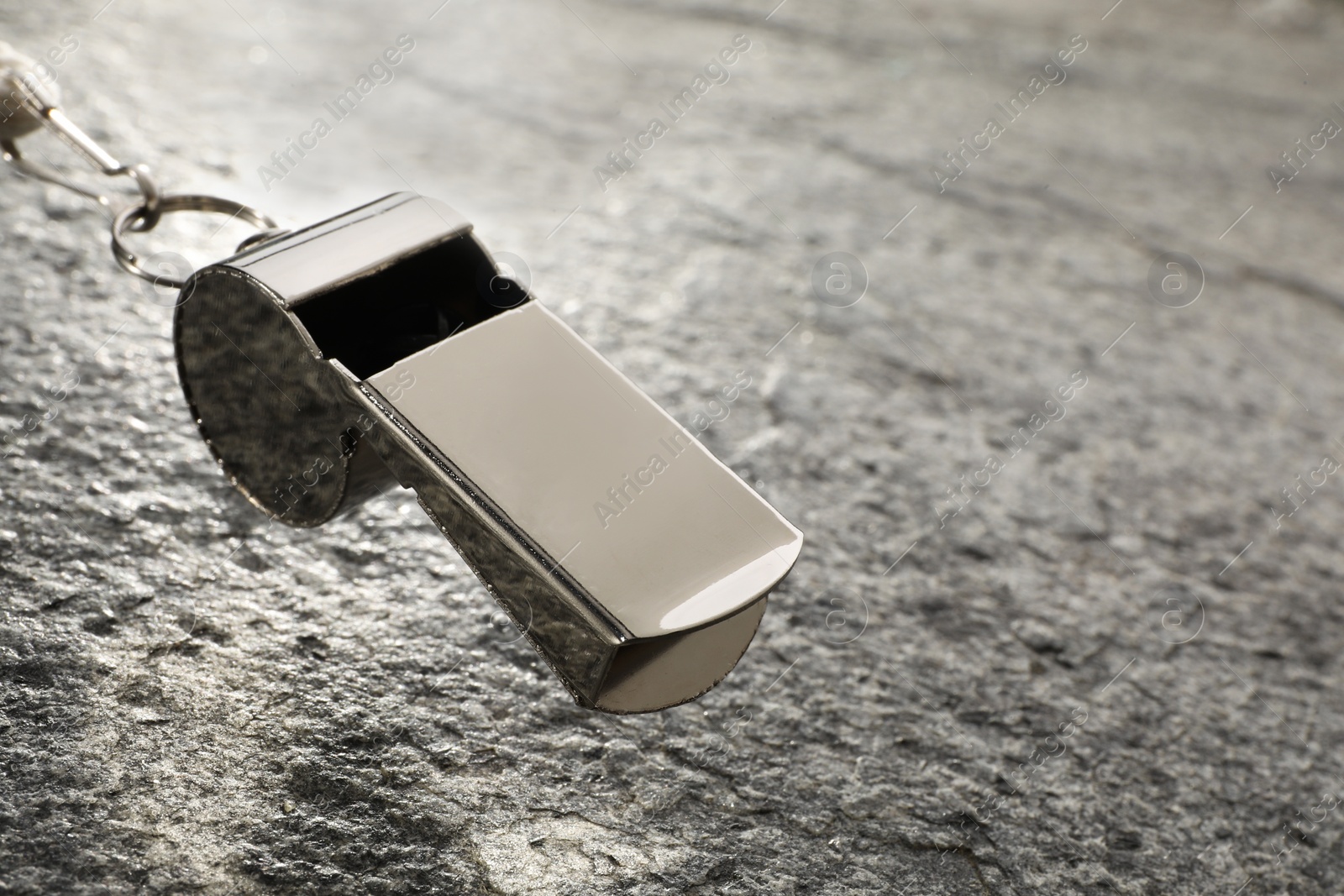 Photo of Referee equipment. Metal whistle on grey textured background, closeup and space for text