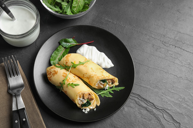 Photo of Delicious thin pancakes with chicken and mushrooms on black table, flat lay