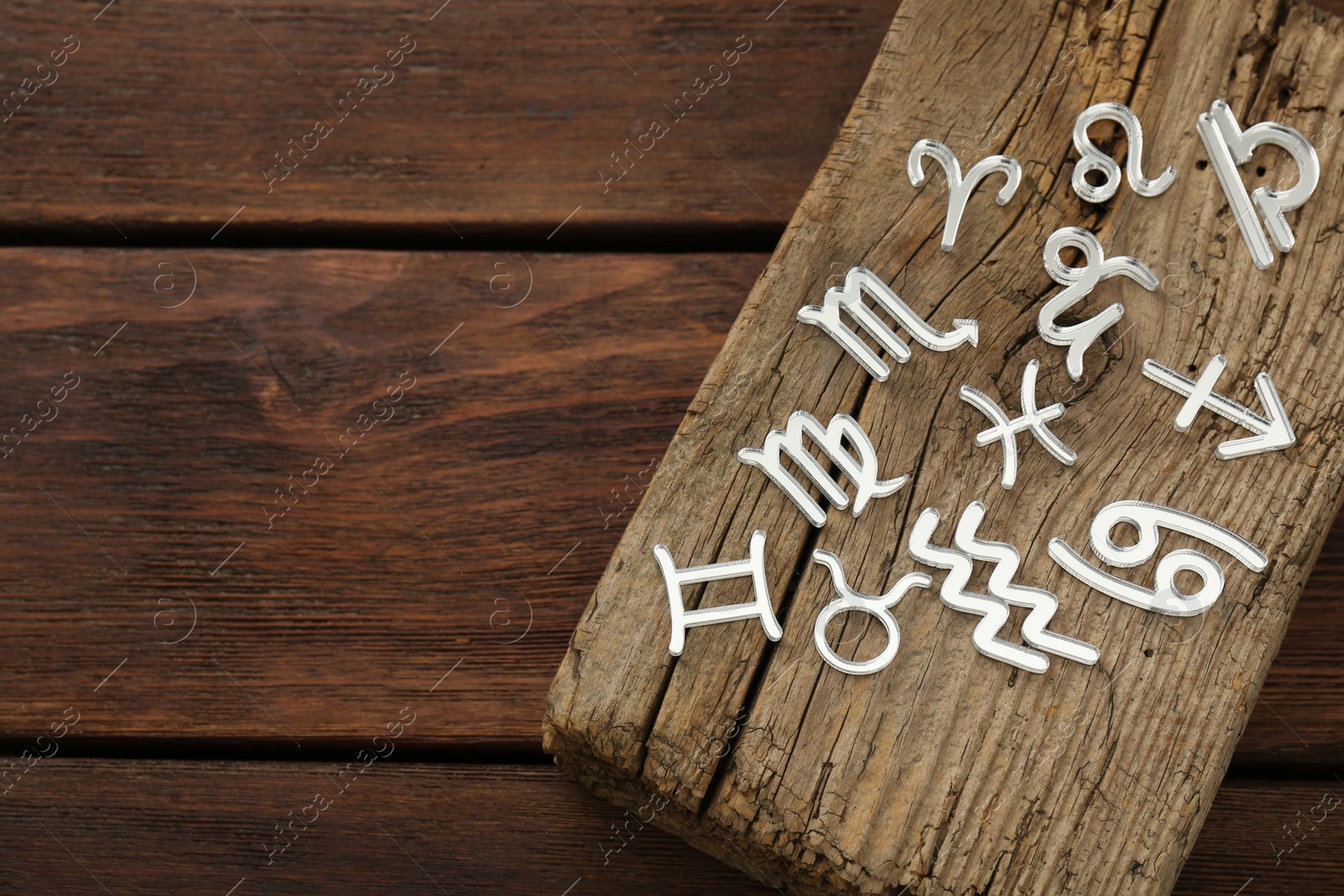 Photo of Zodiac signs on wooden table, above view. Space for text