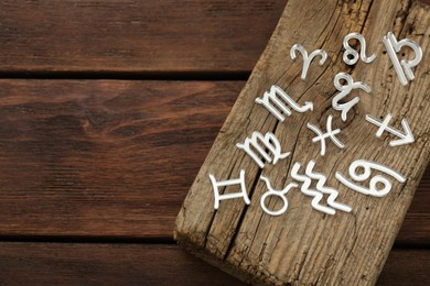 Photo of Zodiac signs on wooden table, above view. Space for text
