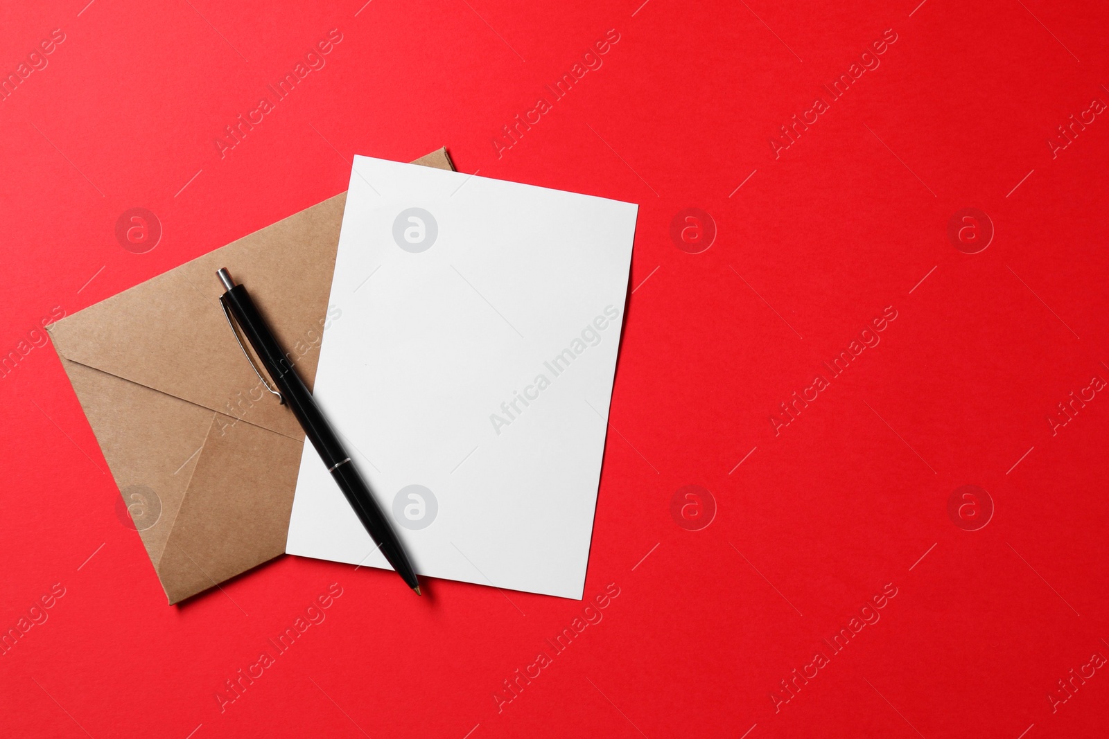 Photo of Blank sheet of paper, letter envelope and pen on red background, top view. Space for text