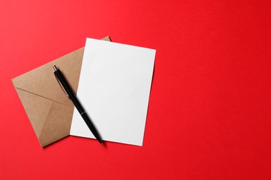 Photo of Blank sheet of paper, letter envelope and pen on red background, top view. Space for text