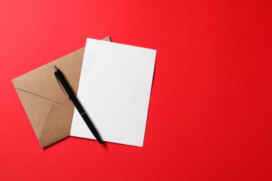 Blank sheet of paper, letter envelope and pen on red background, top view. Space for text