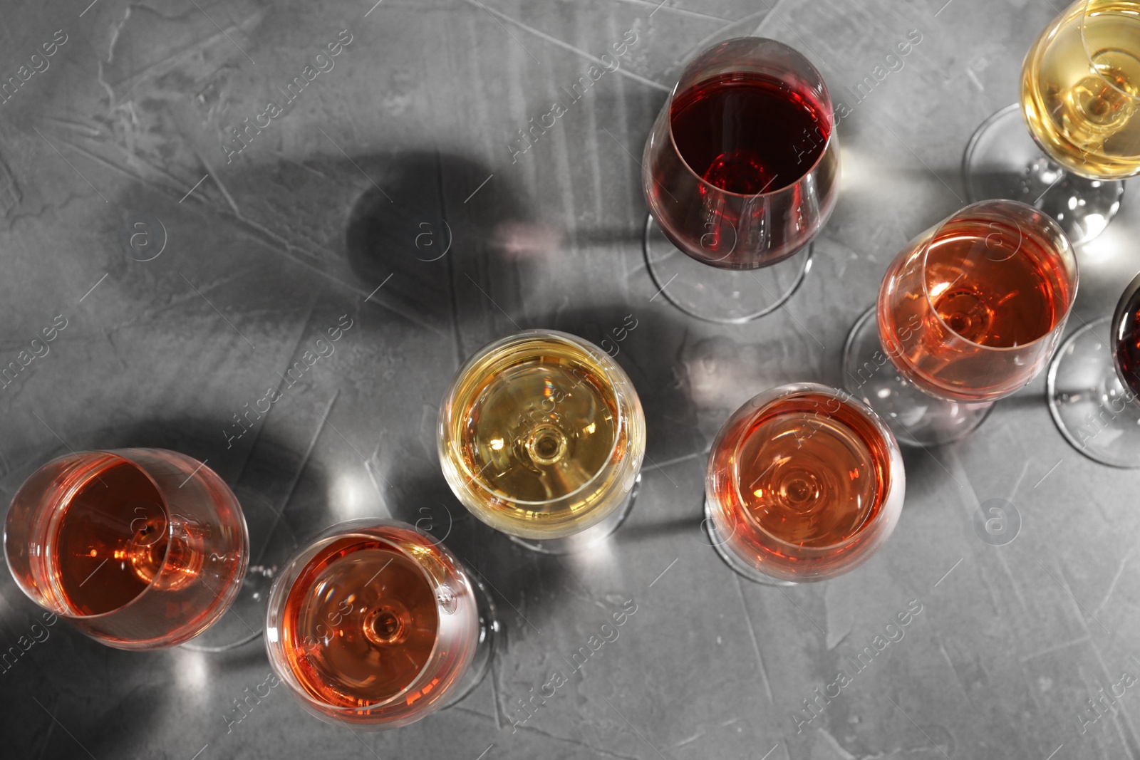 Photo of Different glasses with wine on grey background, flat lay