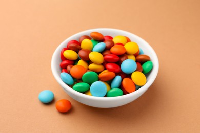 Photo of Tasty colorful candies on light brown background, closeup