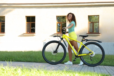 Beautiful young African-American woman with bicycle on city street