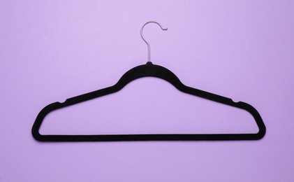 Empty clothes hanger on violet background, top view