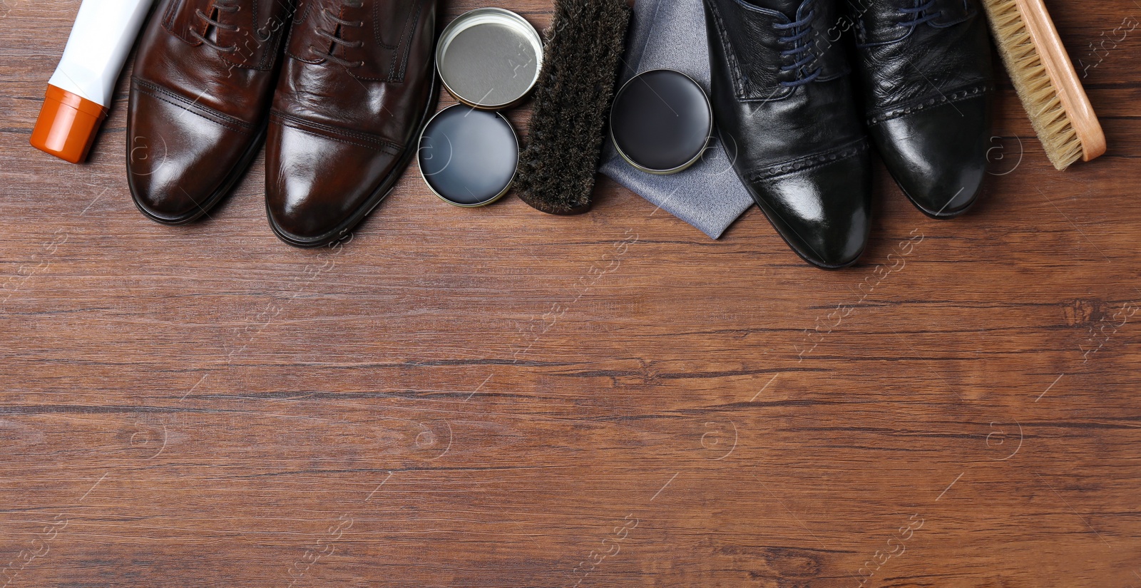 Photo of Flat lay composition with footwear and shoe shine kit on wooden background, space for text