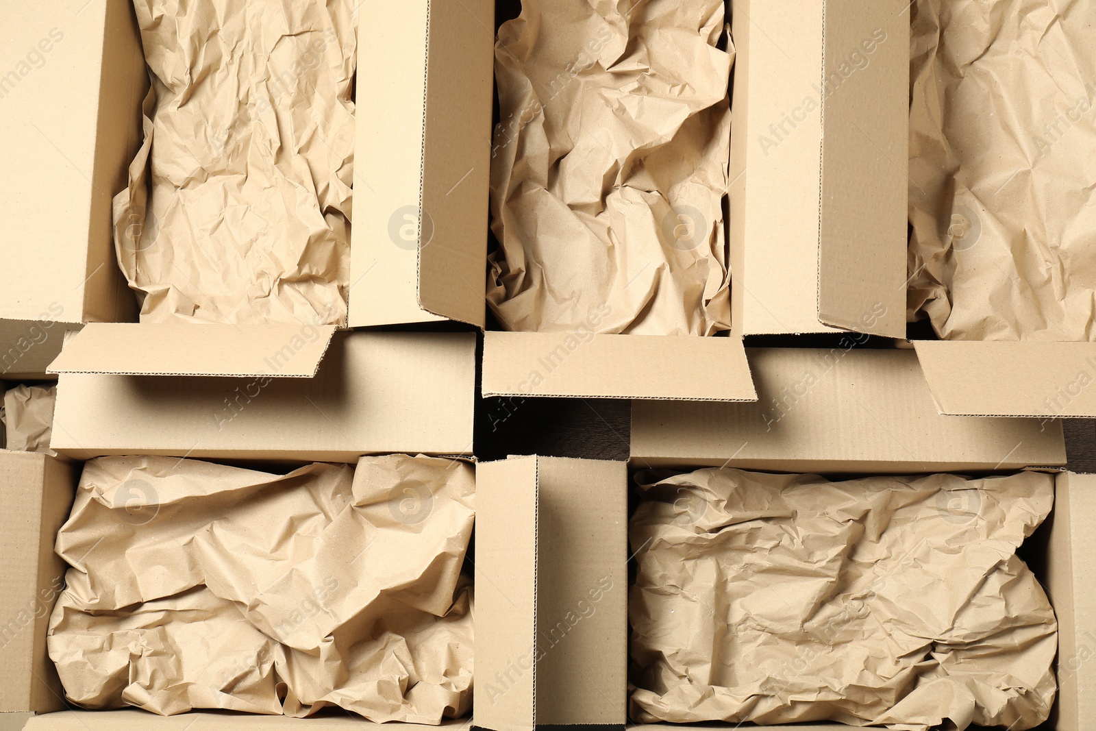 Photo of Open cardboard boxes with crumpled paper, top view. Packaging goods