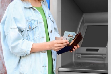 Woman with money near cash machine outdoors, closeup