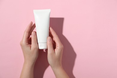 Photo of Woman with tube of hand cream on pink background, top view. Space for text