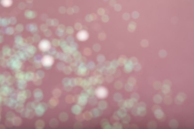 Blurred view of white glitter on pink background. Bokeh effect