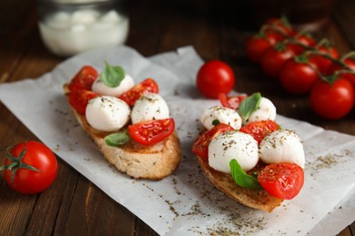 Photo of Delicious sandwiches with mozzarella, fresh tomatoes and basil on wooden table 