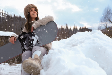 Young snowboarder wearing winter sport clothes outdoors, low angle view