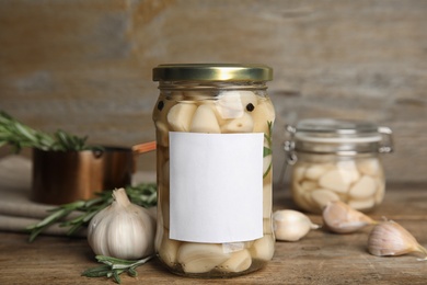 Composition with jars of pickled garlic on wooden table