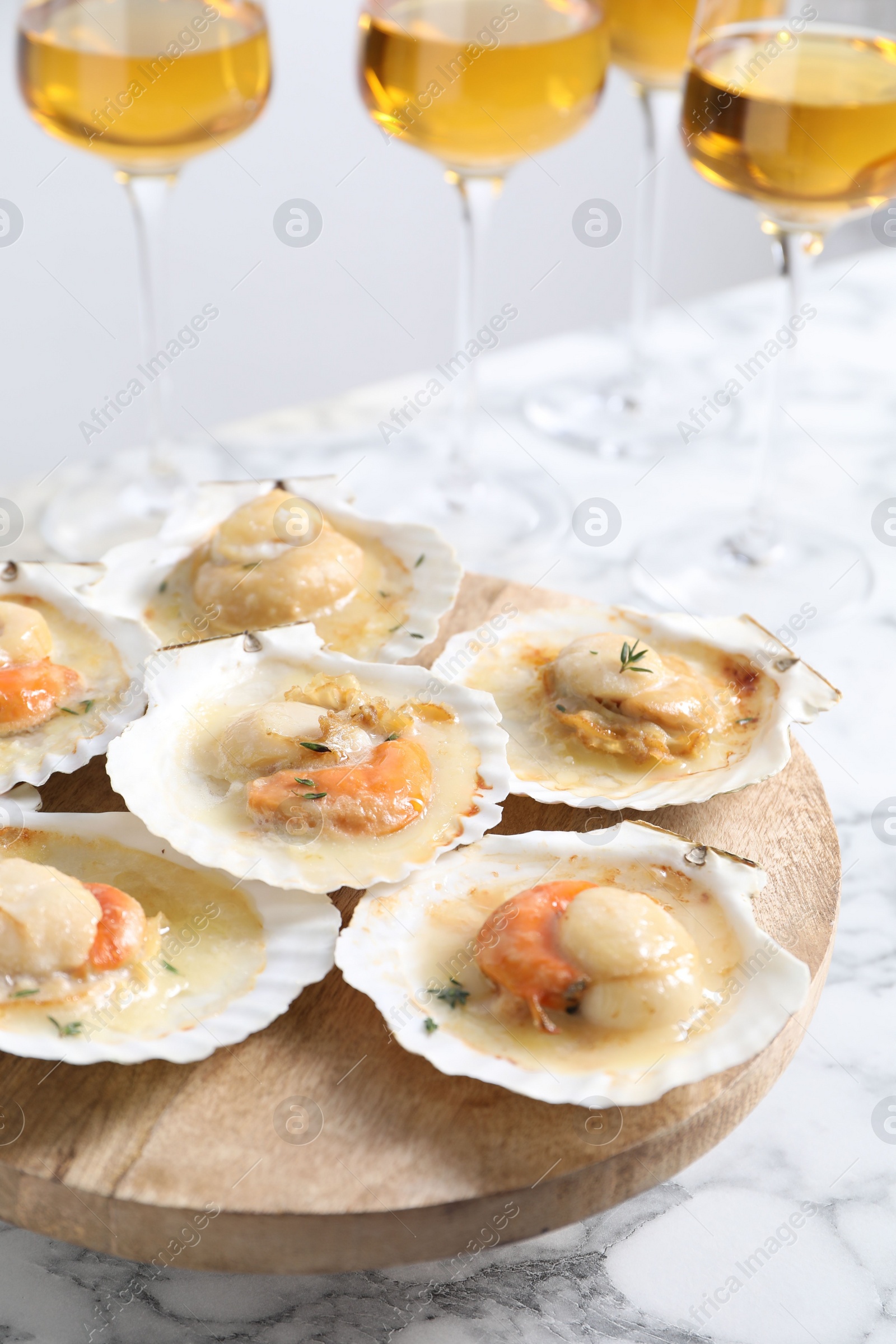 Photo of Fried scallops in shells and wine on white marble table