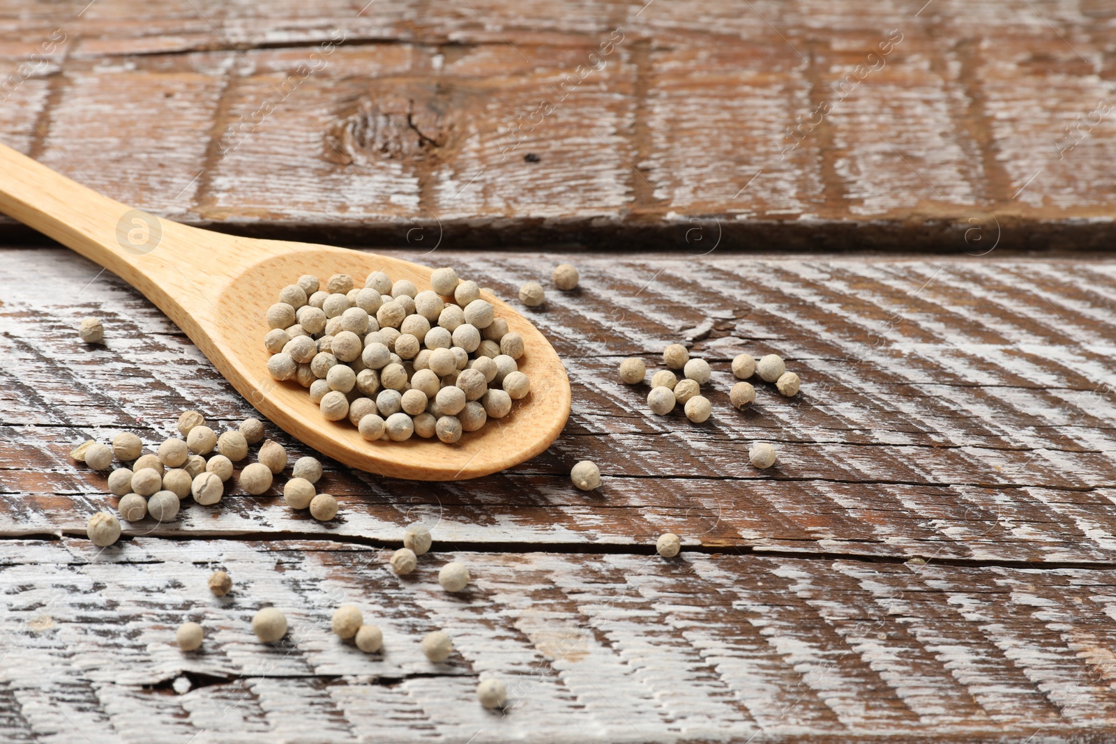 Photo of Aromatic spice. White pepper in spoon on wooden table, closeup. Space for text