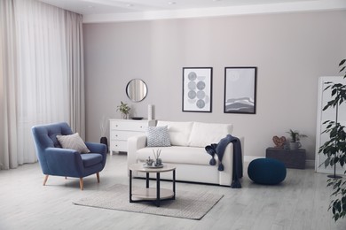 Stylish living room interior with white sofa, armchair and small coffee table