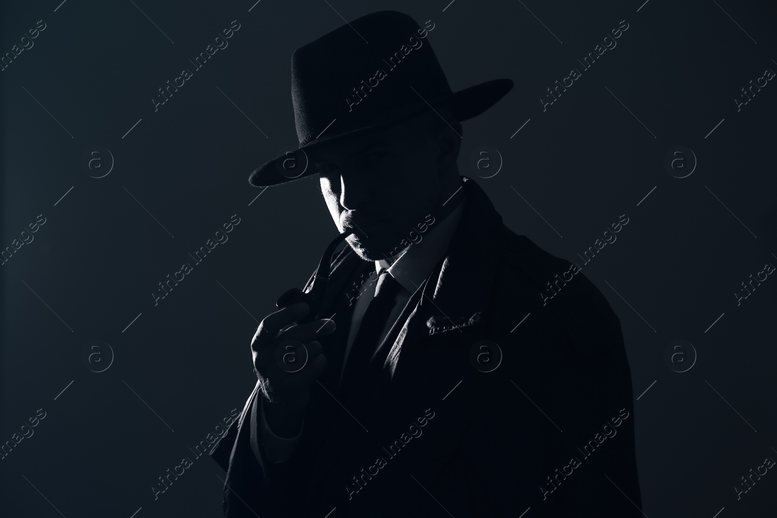 Photo of Old fashioned detective with smoking pipe on dark background, black and white effect