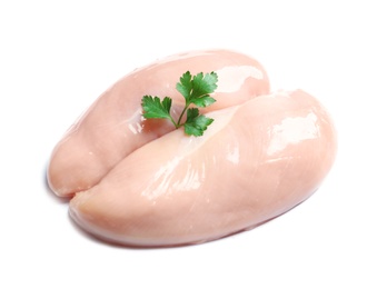 Raw chicken breasts with parsley on white background