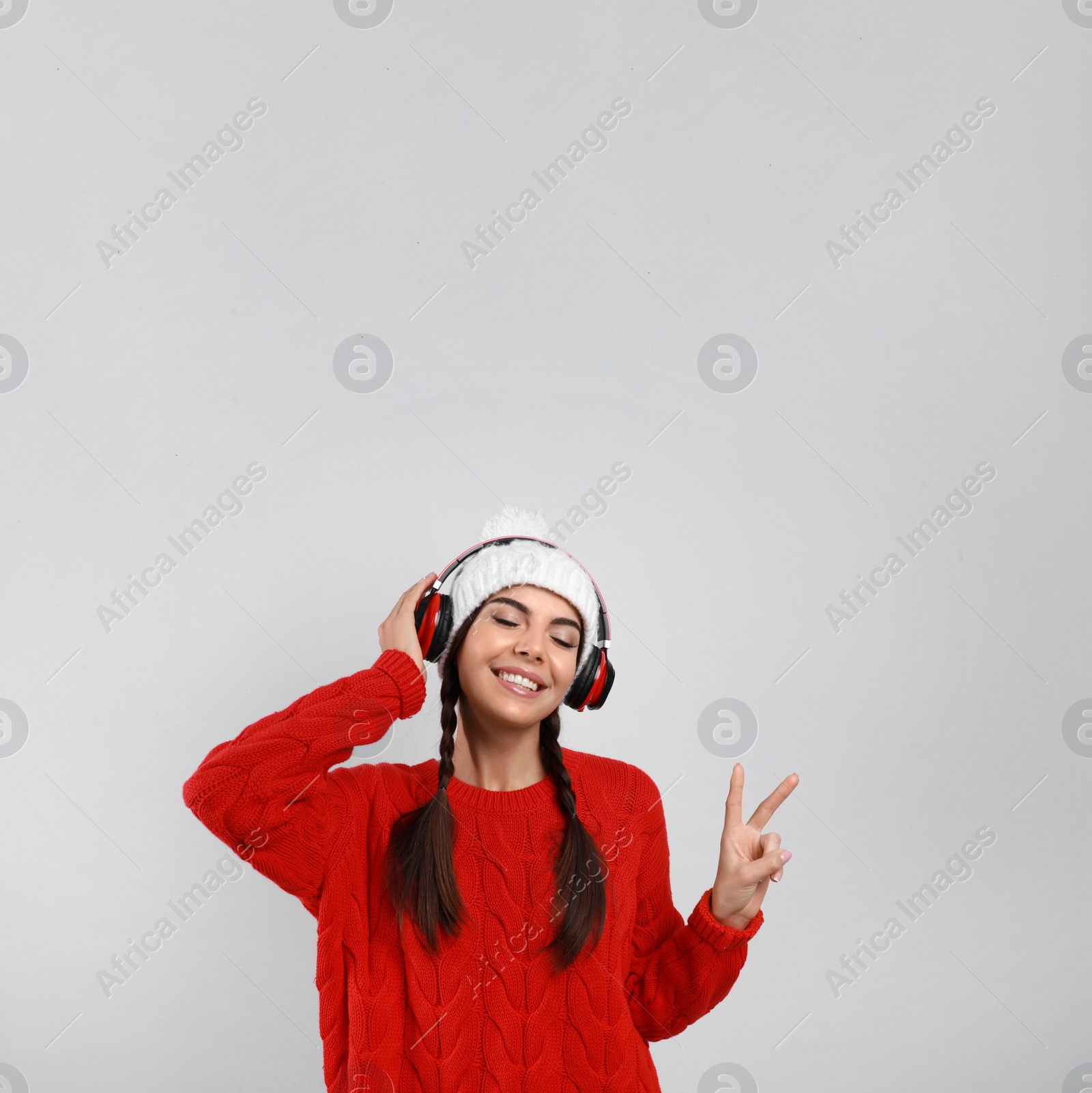 Photo of Young woman listening to music with headphones on grey background