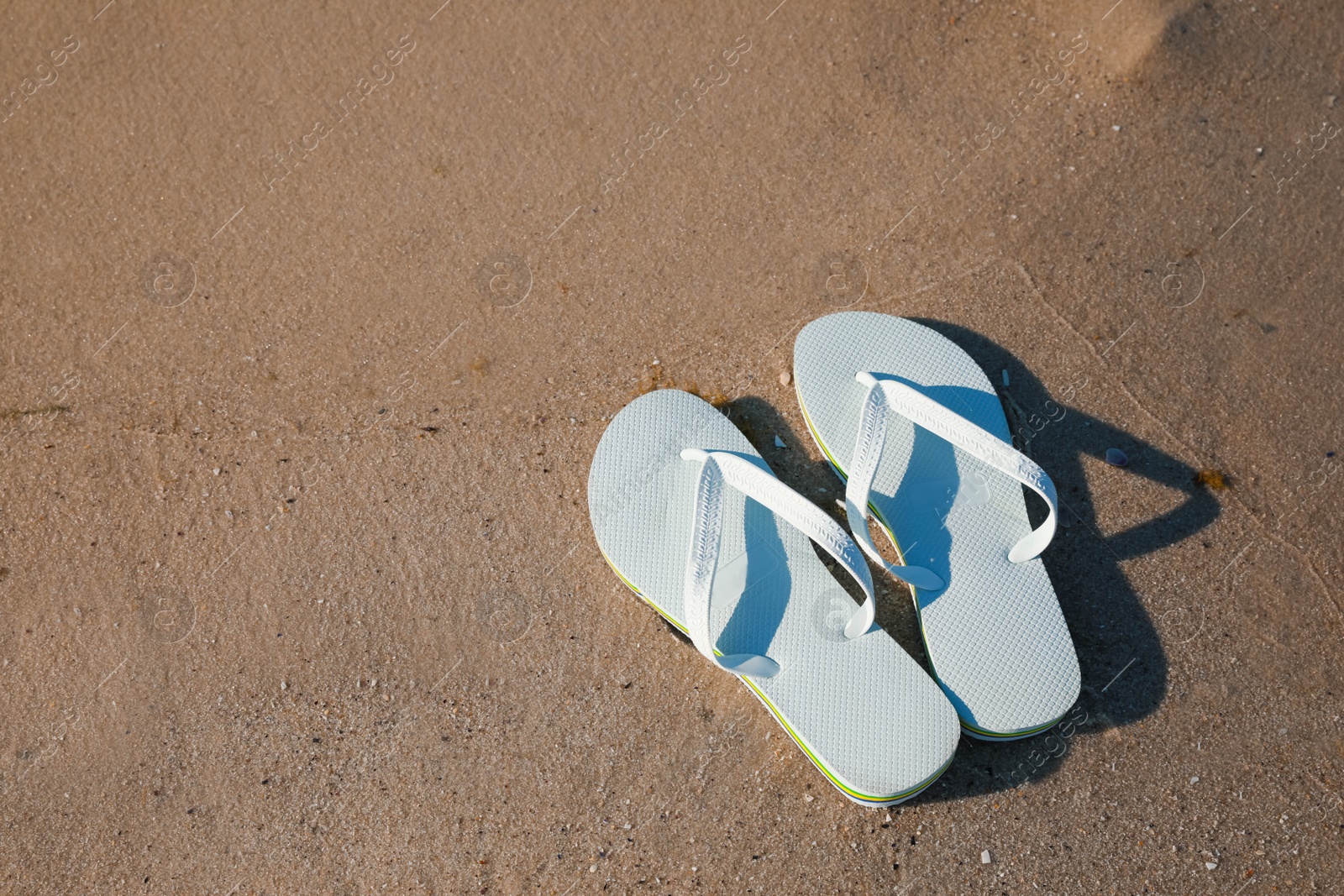 Photo of Stylish flip flops on beach, above view. Space for text