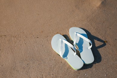 Stylish flip flops on beach, above view. Space for text