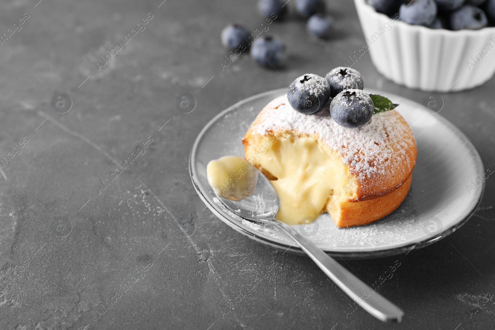 Photo of Tasty vanilla fondant with white chocolate and blueberries on grey table, space for text