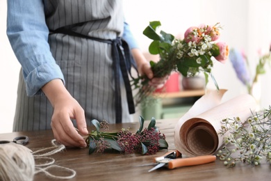 Female florist creating beautiful bouquet at table