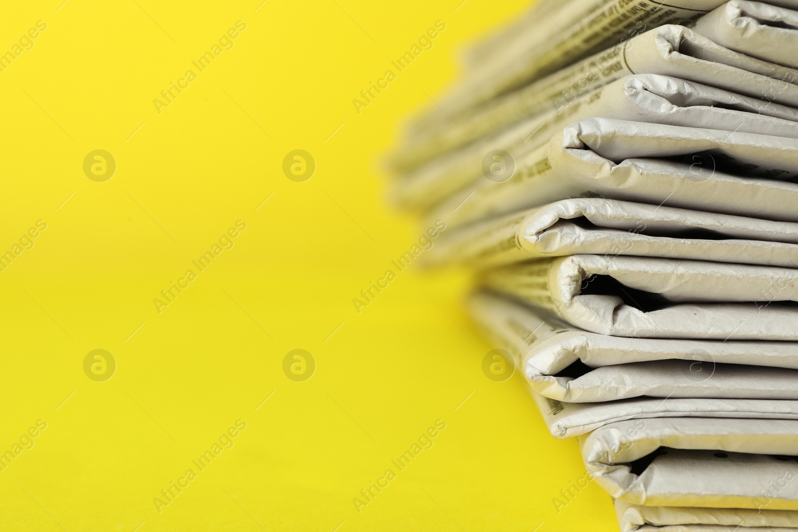 Photo of Stack of newspapers on yellow background, closeup with space for text. Journalist's work