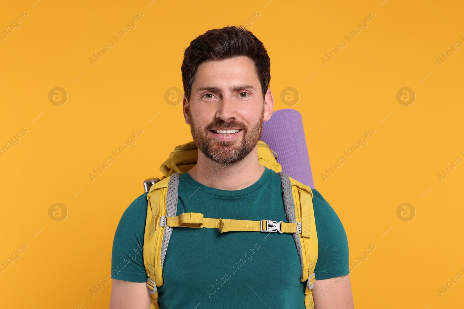 Photo of Happy man with backpack on orange background. Active tourism