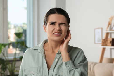 Photo of Young woman suffering from ear pain at home