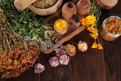 Jar, bottles of essential oils and different herbs on wooden table, above view. Space for text