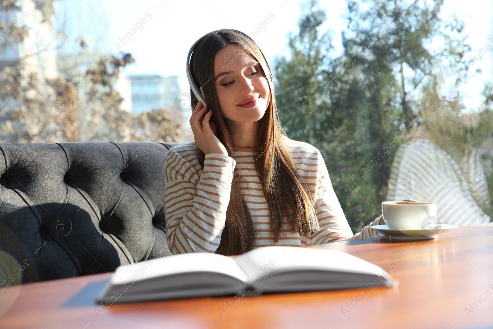 Photo of Woman listening to audiobook at table in cafe