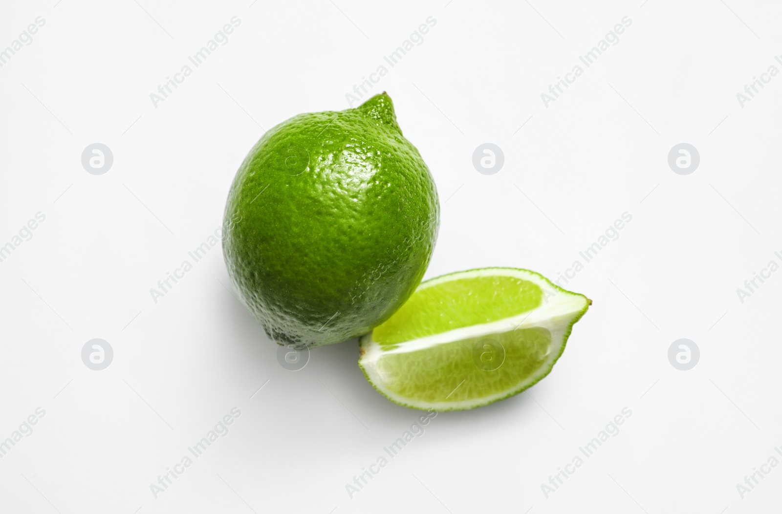 Photo of Whole and cut fresh juicy limes on white background, top view