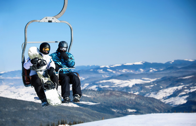 Photo of People using chairlift at mountain ski resort, space for text. Winter vacation