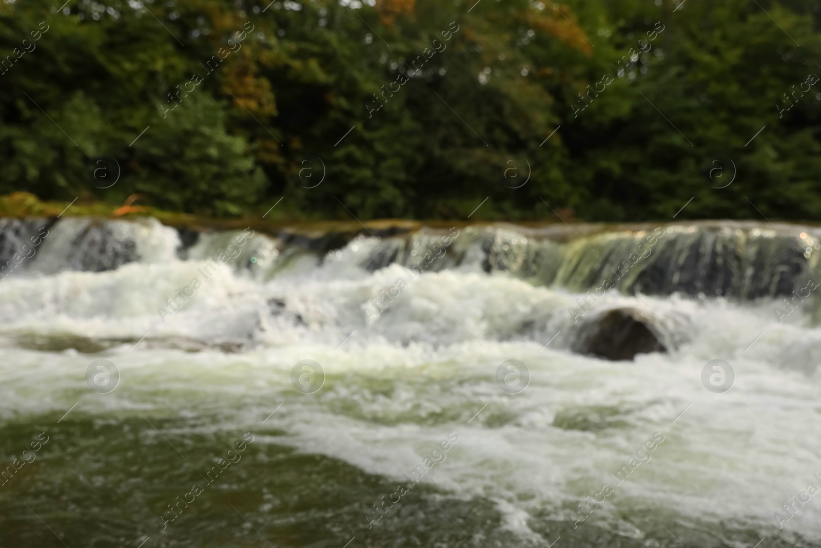 Photo of Blurred view of river with rapids near forest