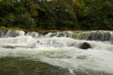 Blurred view of river with rapids near forest