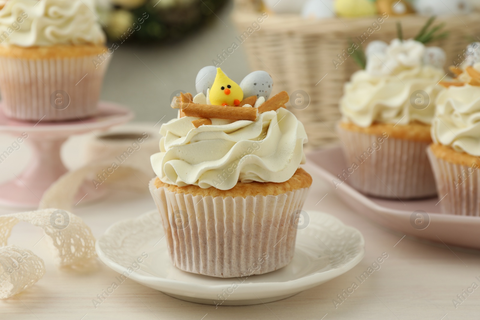 Photo of Tasty Easter cupcakes with vanilla cream on light wooden table