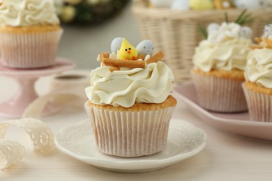 Photo of Tasty Easter cupcakes with vanilla cream on light wooden table