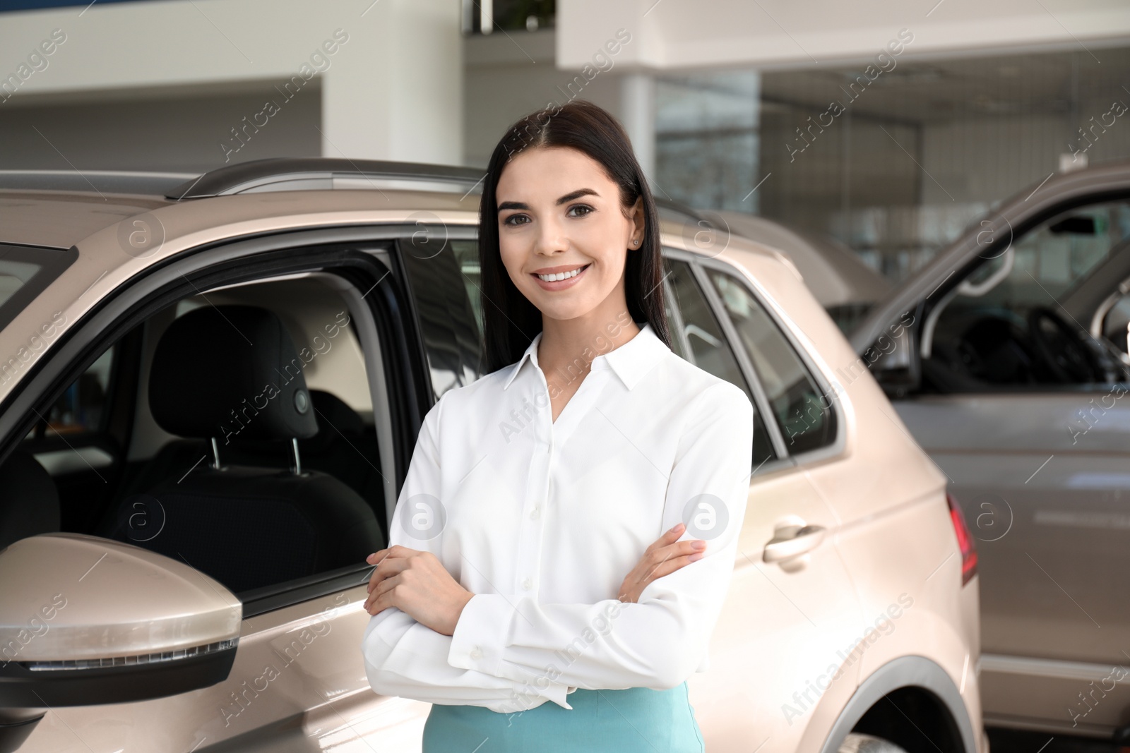 Photo of Young saleswoman near new car in dealership