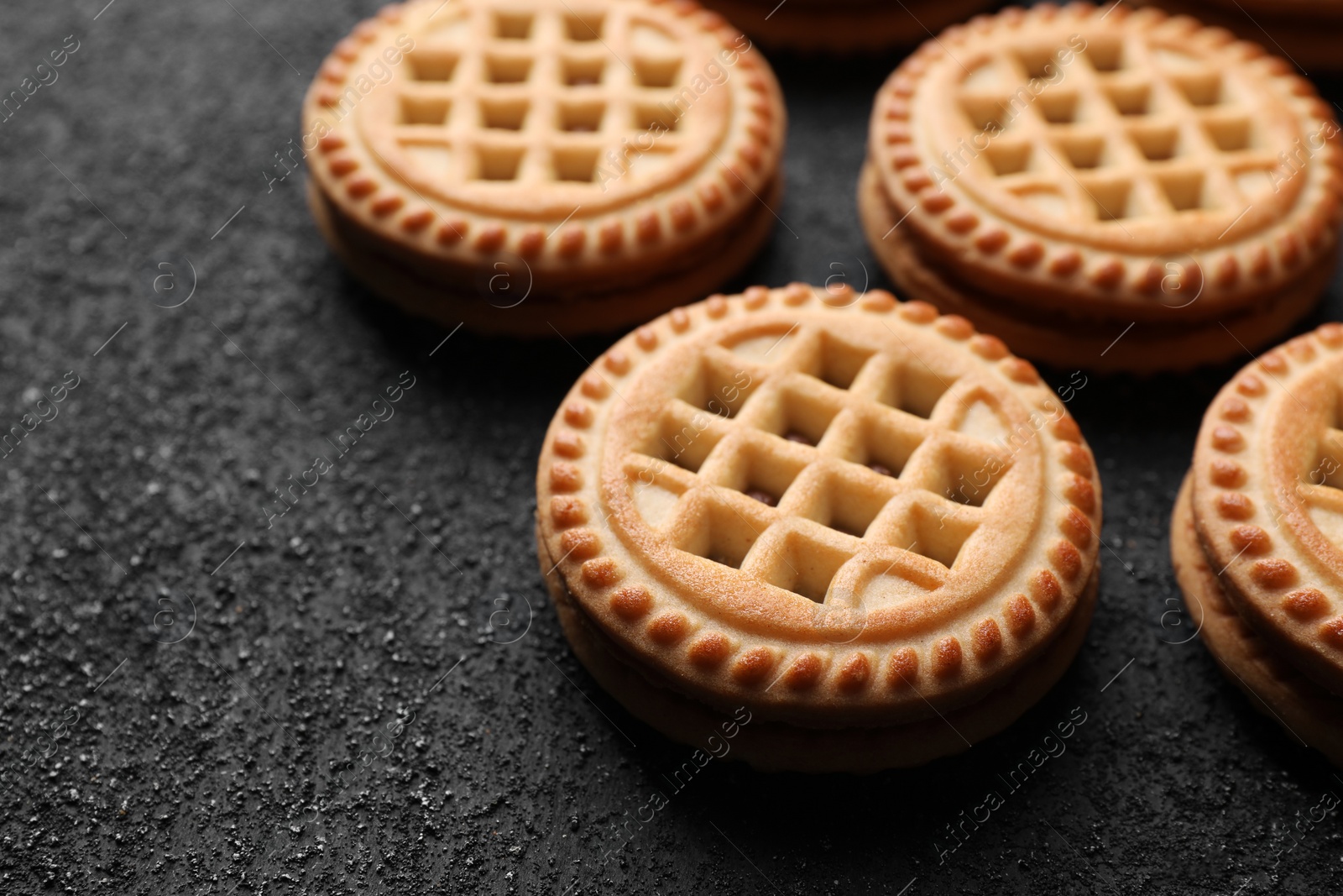 Photo of Tasty sandwich cookies with cream on black textured background, closeup. Space for text