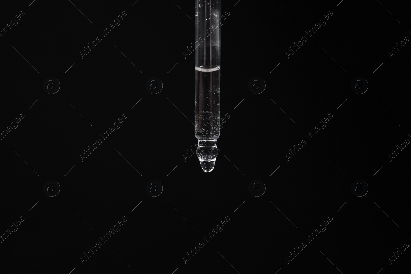 Photo of Dripping cosmetic serum from pipette against black background