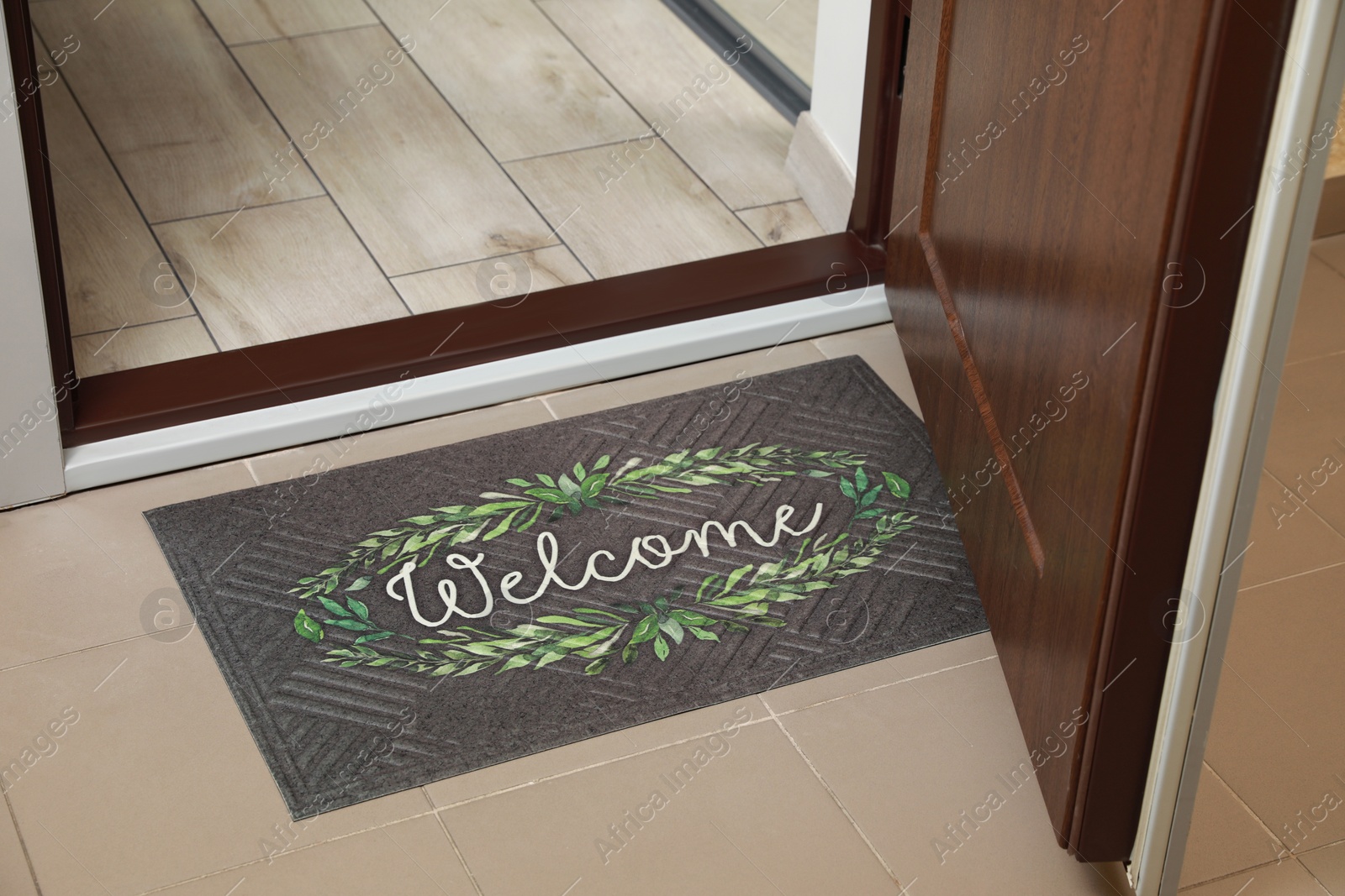 Photo of Beautiful doormat with word Welcome on floor near entrance